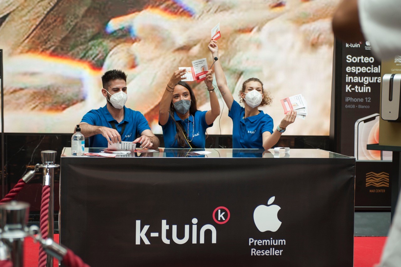 three people at a a hi tech store opening event holding a raffle