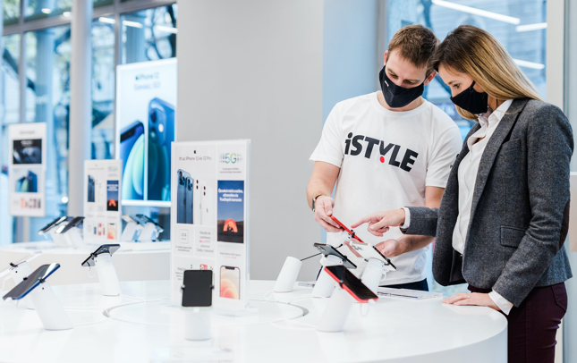 un homme en t-shirt et une femme en costume d'affaires discutent d'iPhone dans un site de vente au détail de haute technologie
