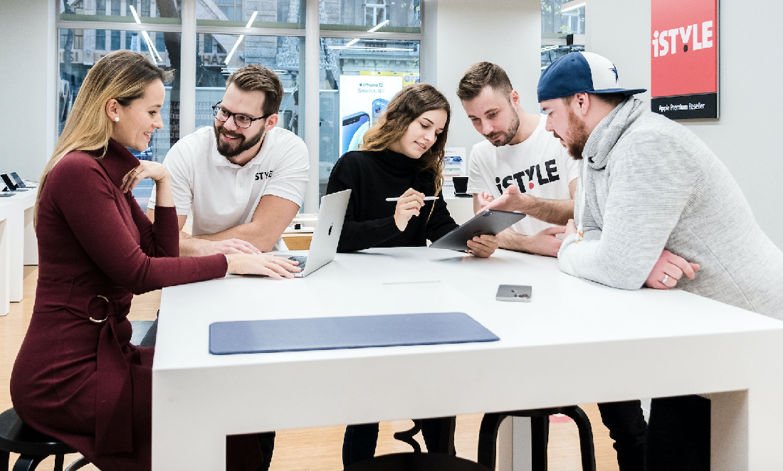 cinq personnes regardent des ordinateurs portables Apple dans un magasin de haute technologie