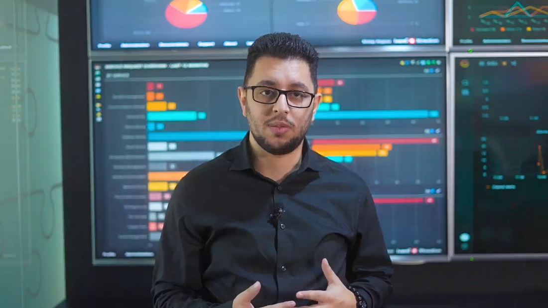 shows a man standing in front of digital display screens