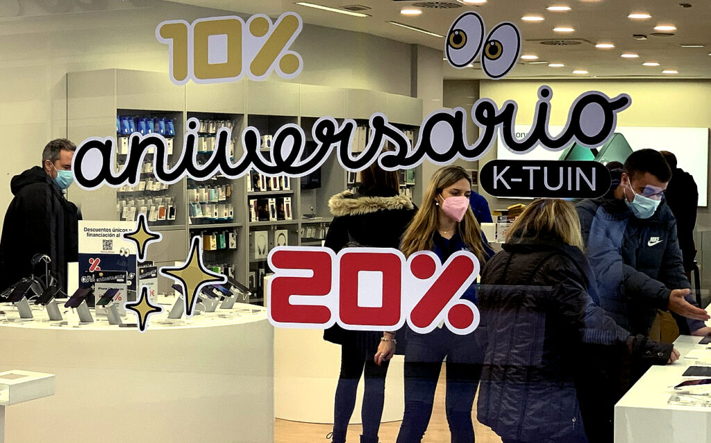 en regardant à travers une vitrine, on peut voir des gens examiner des produits de haute technologie