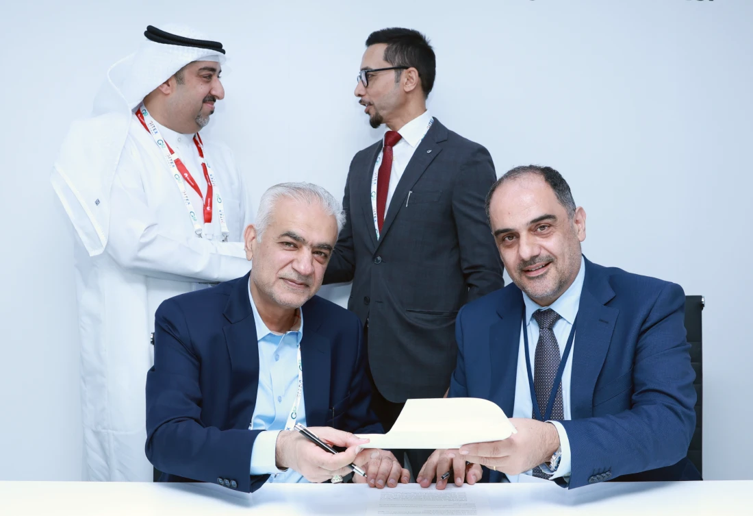 four men are seen with two in the foreground holding an agreement, which they just signed