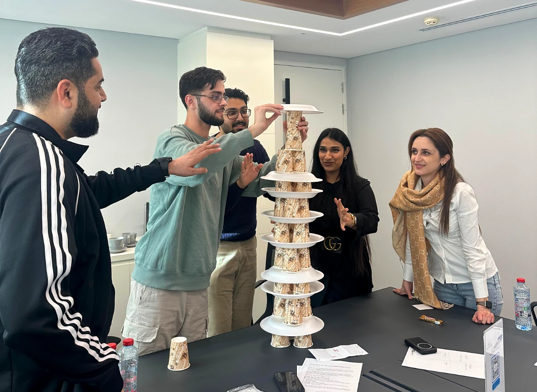 Five people are seen creating a tower made from paper cups