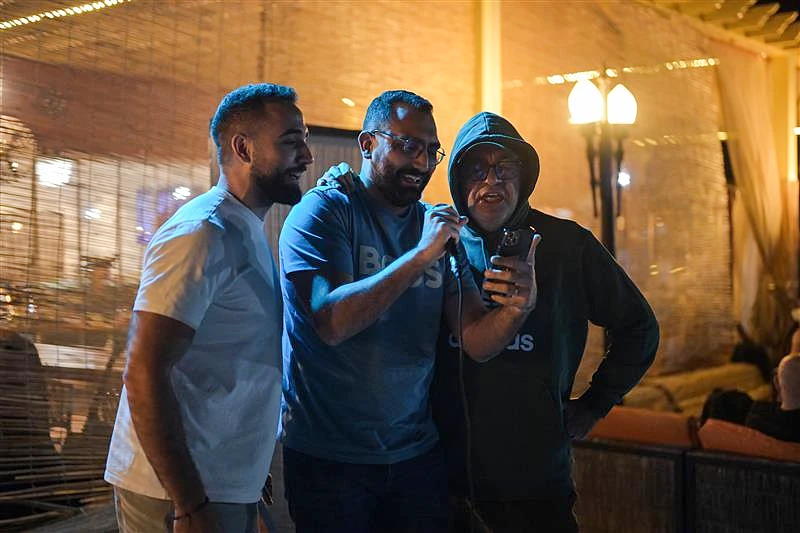 three men are looking at a mobile phone