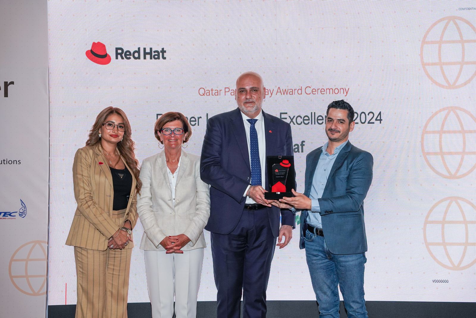 two women and two men are seen in front of a presentration screen with a trophy being handed over