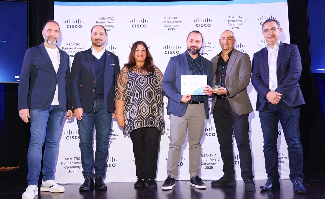 Six people are present on a stage as an award certificate is handed to one of them