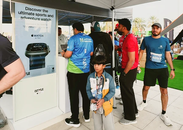 Un jeune, portant une médaille de coureur, est visible devant le stand iSTYLE.