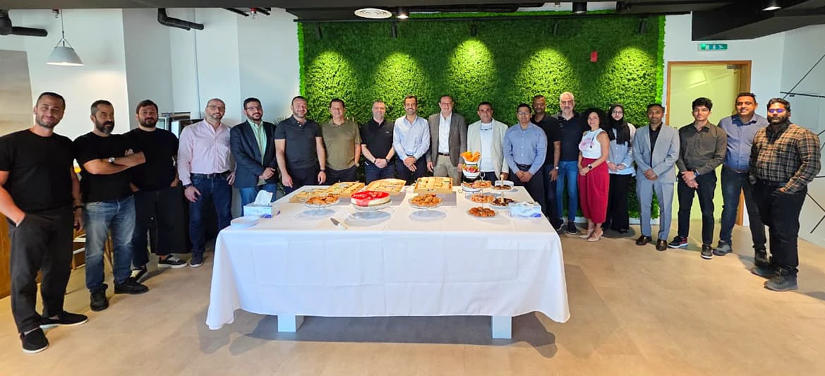 a group photograph with people arranged around a table with celebration snacks on it
